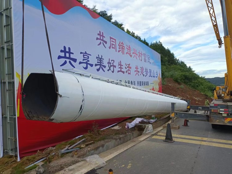 吊车把在地面拼好的牌体吊起，立柱已立在弯道旁