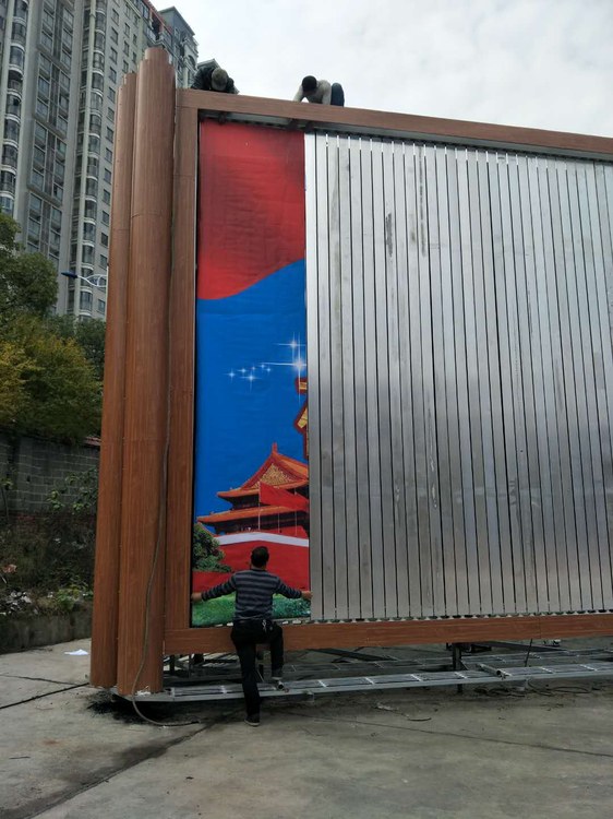 工人在广告塔牌体上绷贴喷绘画面,上下配合压条固定